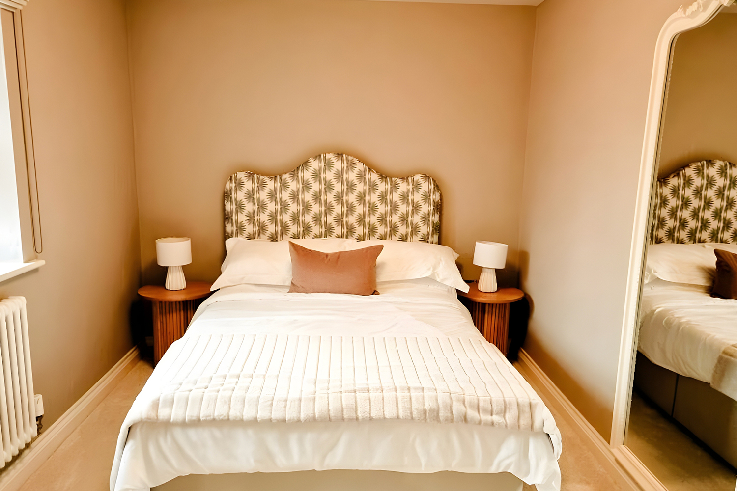 A calm, neutral bedroom featuring a patterned statement headboard, soft lighting and simple, cosy styling for a relaxed and welcoming space.
