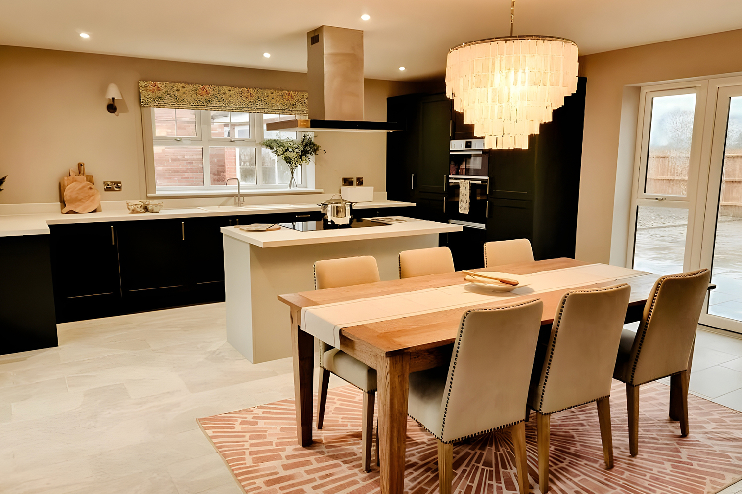 Open-plan kitchen diner with a central island, pendant lighting and a wooden dining table, combining modern cabinetry with soft neutral tones.