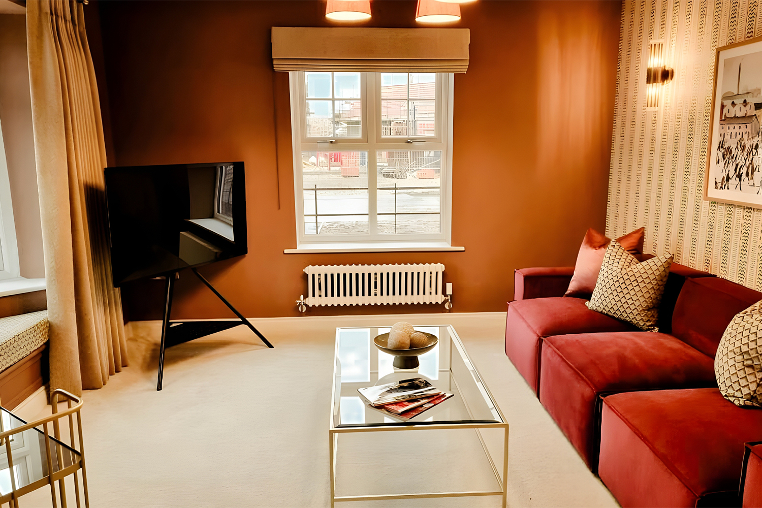 A cosy lounge with warm earthy tones, a red velvet sofa and contemporary decor, styled for comfortable evenings at home.