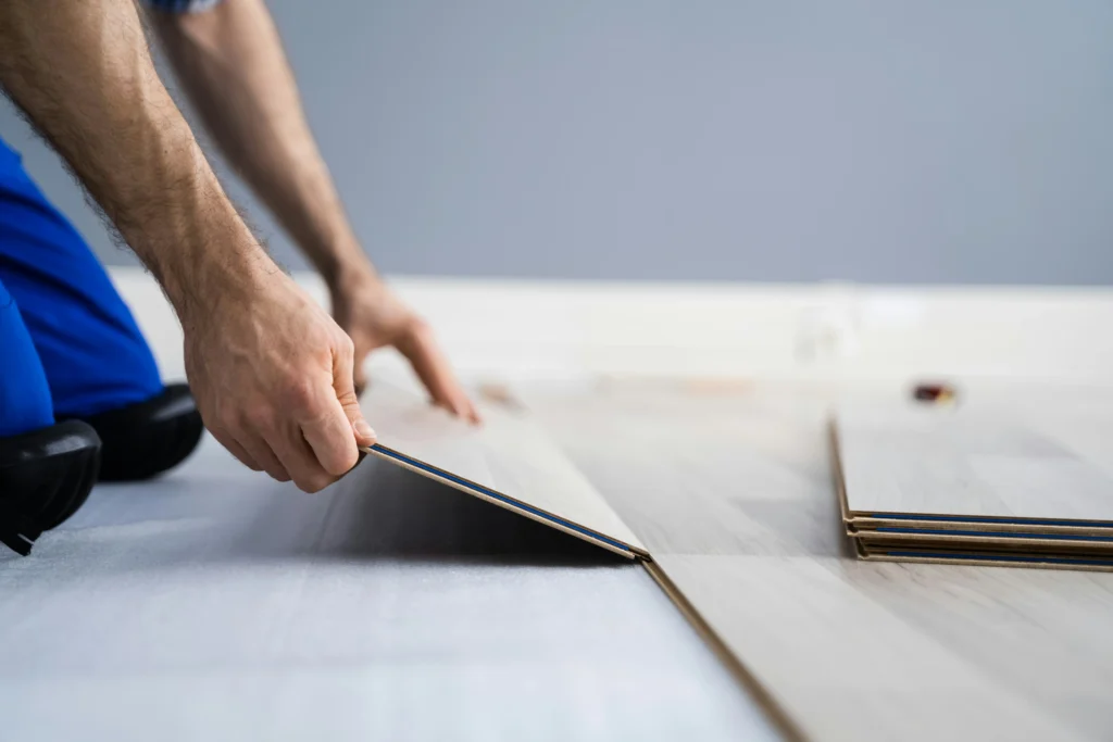 Close-up of a person fitting wooden flooring planks during home installation.