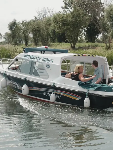 Broadgate Homes branded water taxi carrying people along a river.