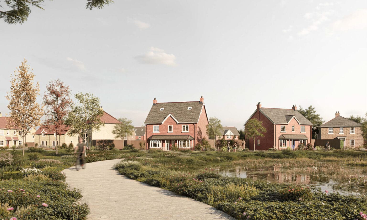 A peaceful lakeside setting at Gleneagles Drive with pathways, planting, and views of red-brick homes overlooking the water, offering a sense of open space and nature woven into the development.