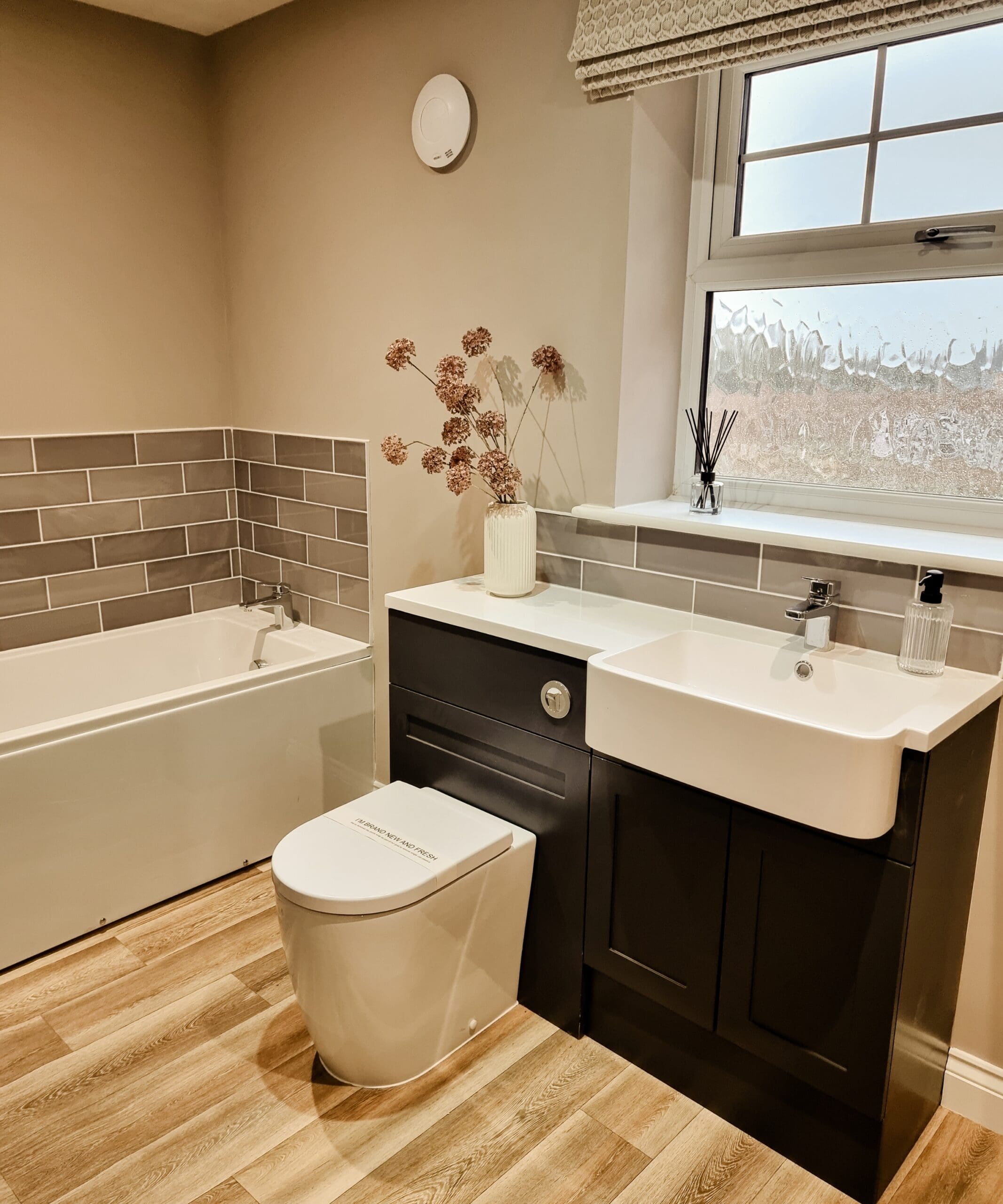 Stylish bathroom with a bath, dark cabinetry, and elegant tiled detailing - combining practicality with refined design in a Broadgate home.