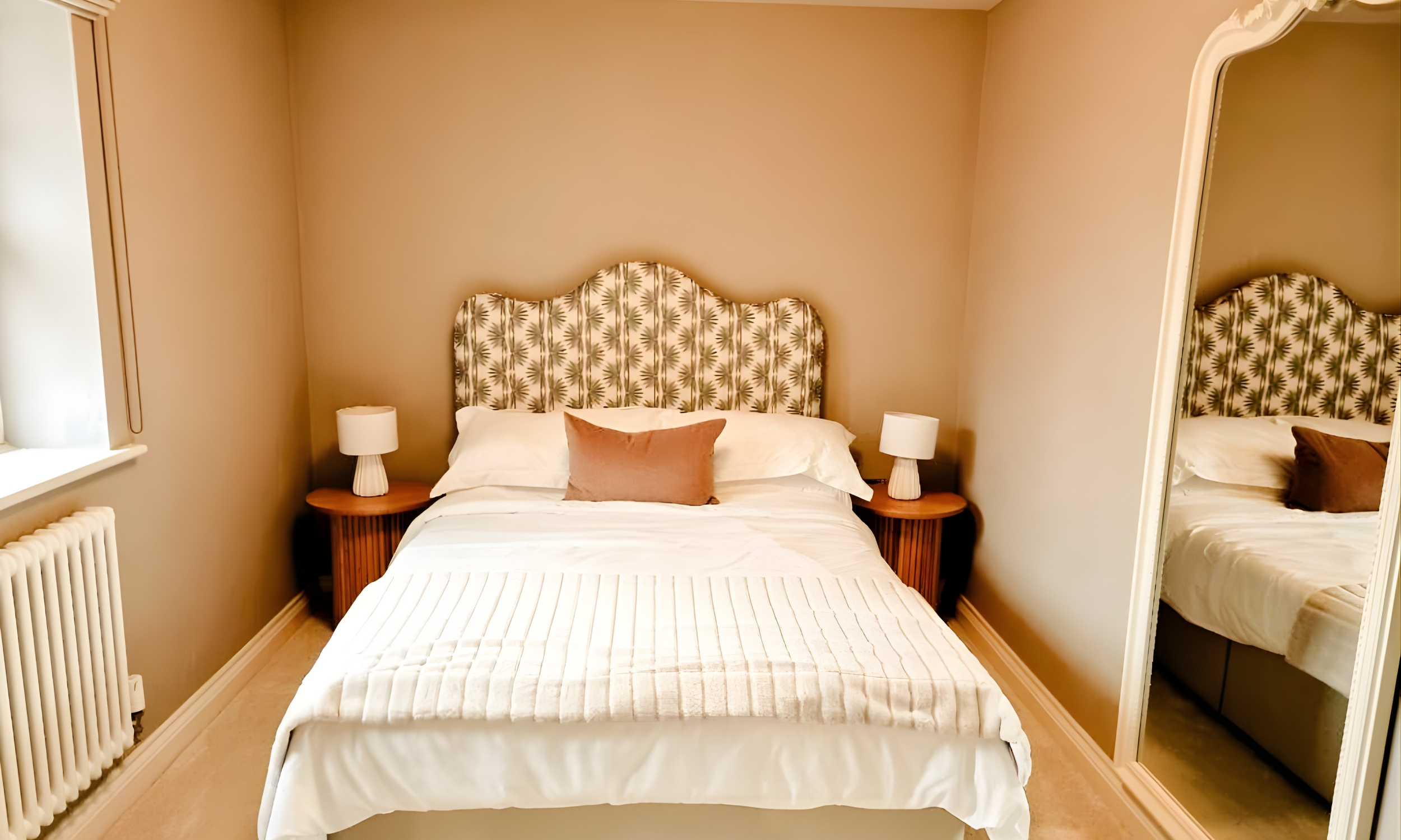 A cosy bedroom with a patterned headboard, soft neutral tones, and warm lighting - designed for restful nights at The Furlongs, Holland Park.