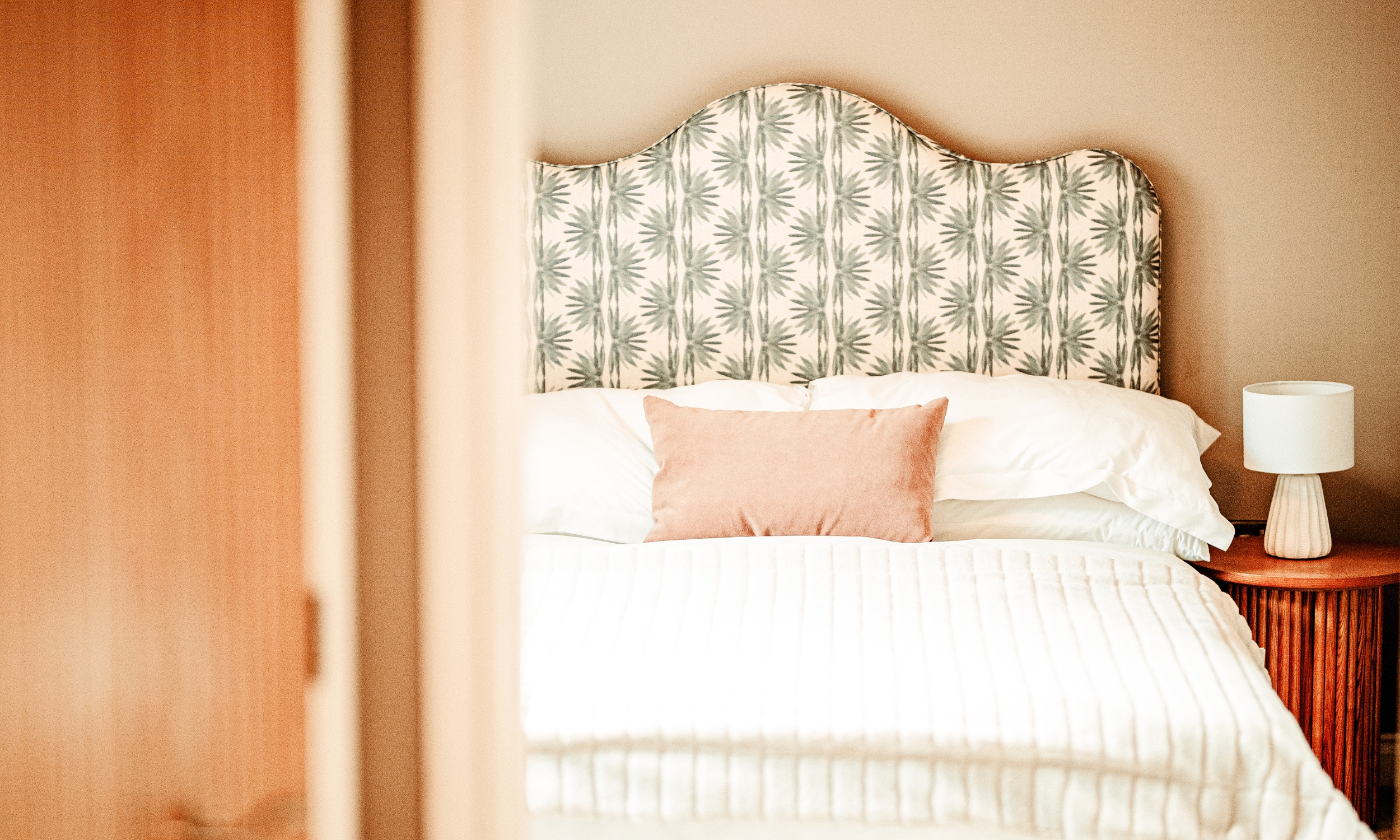 Serene bedroom with a soft patterned headboard and muted décor, reflecting Broadgate’s blend of comfort and contemporary design.