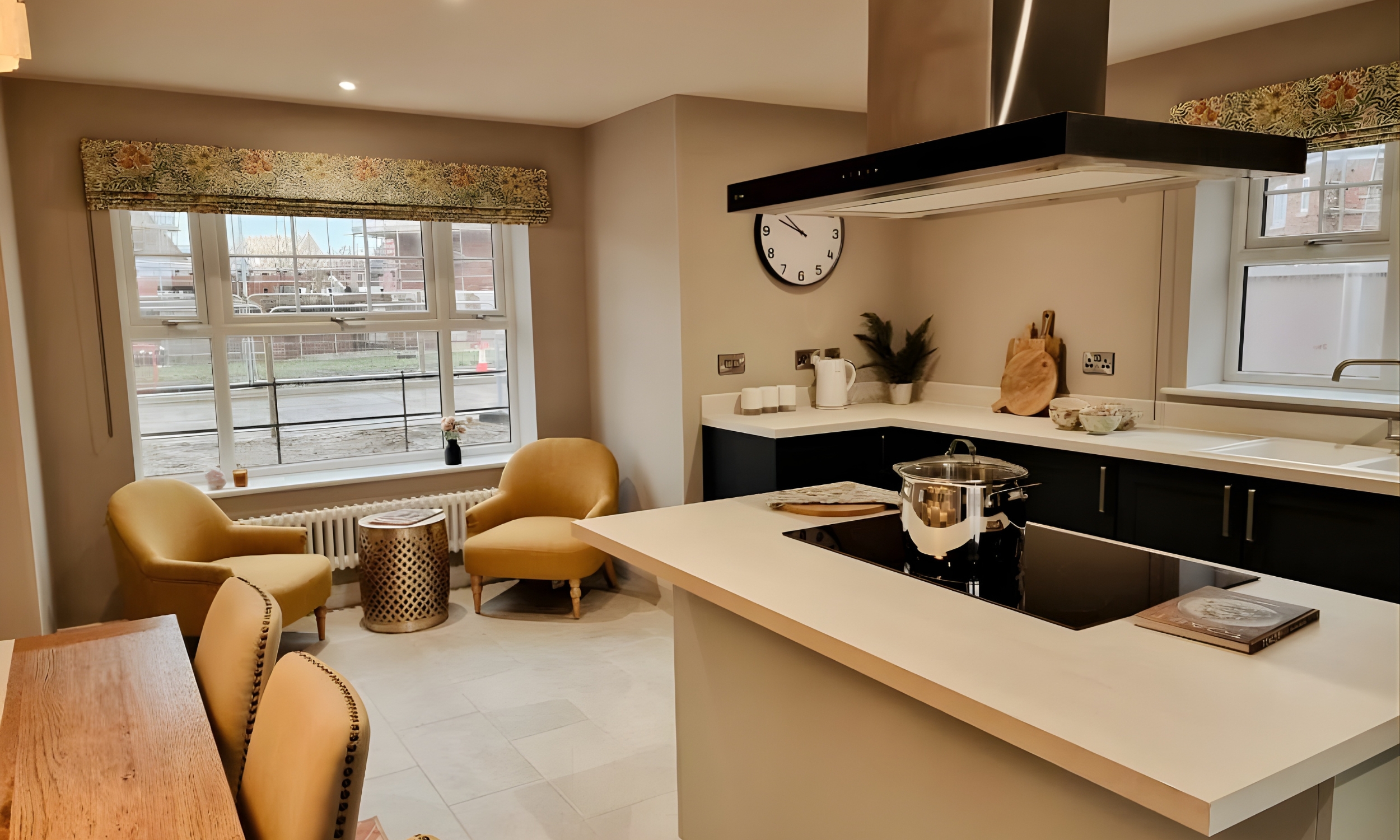 Bright and welcoming kitchen with mustard accent chairs by a bay window, combining functionality and comfort for relaxed family living at The Furlongs.