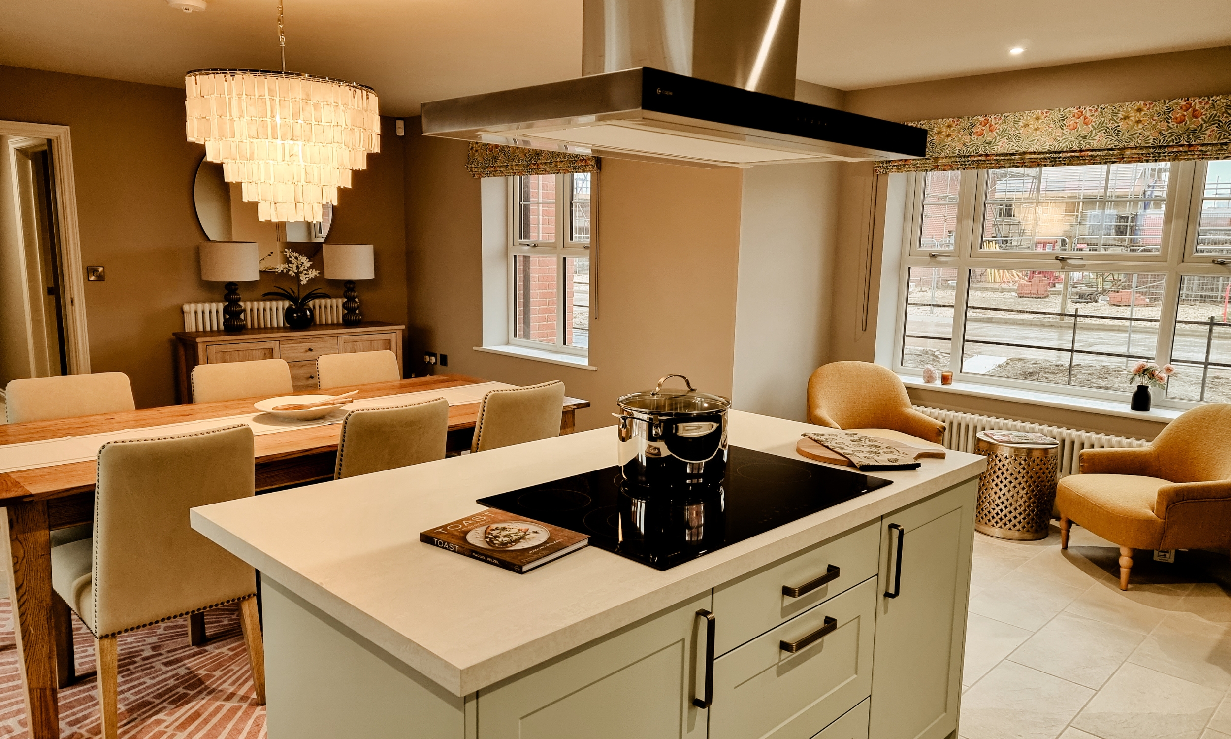 Open-plan kitchen and dining room with an island hob, soft lighting, and cosy window seating - designed for shared moments at The Furlongs, Holland Park.