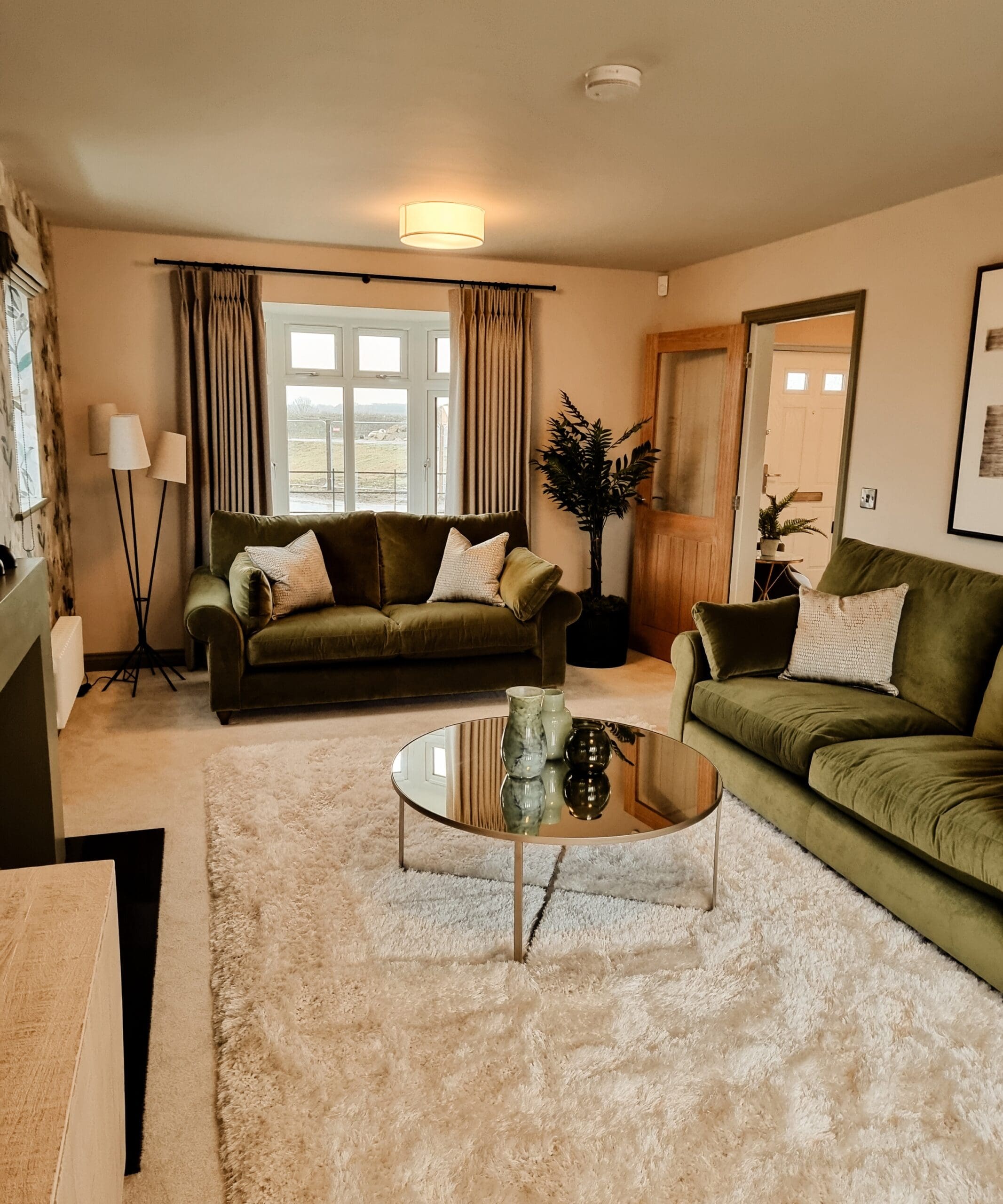 Portrait view of the lounge highlighting plush green sofas, warm lighting, and a mirrored coffee table - showcasing Broadgate’s refined interior design.