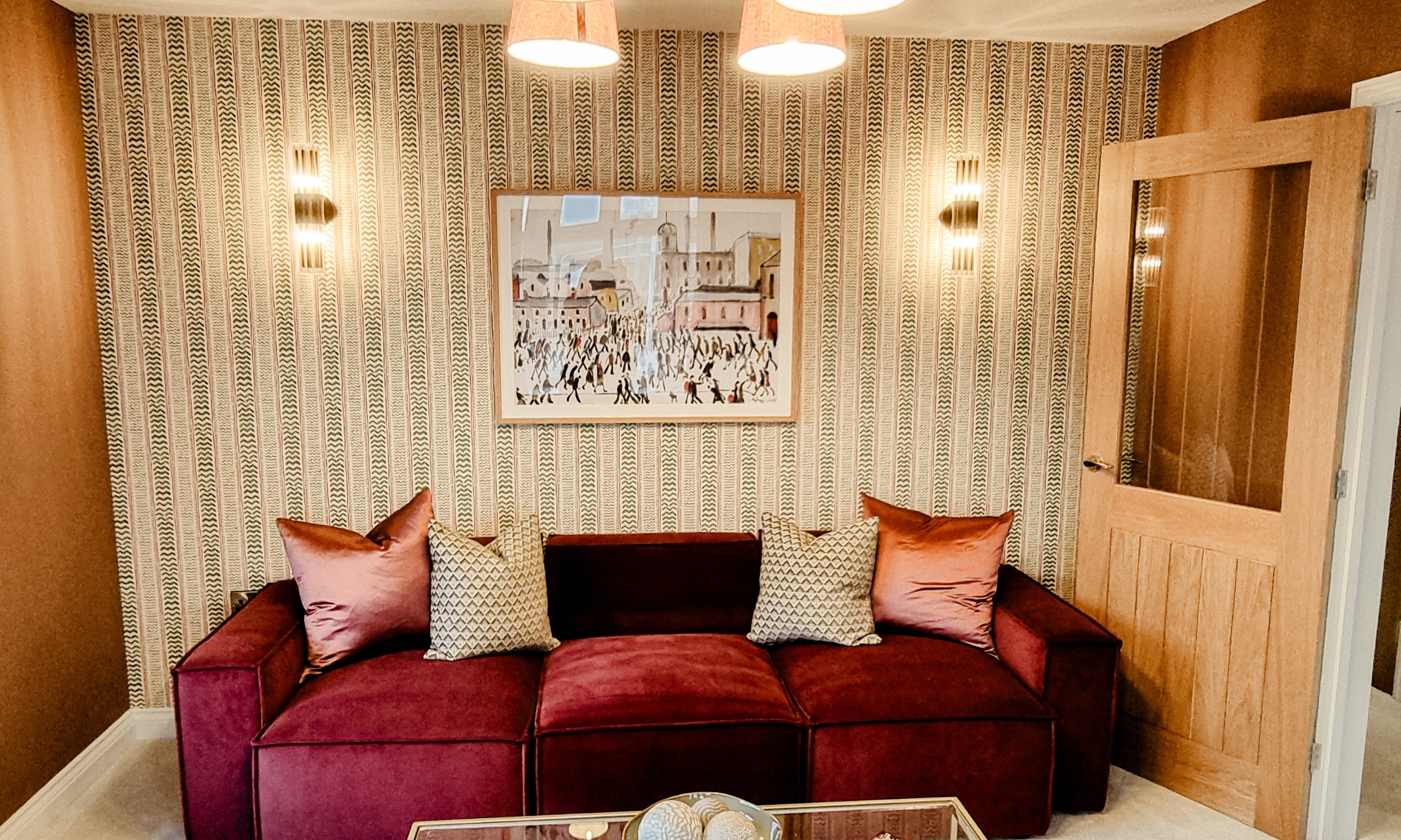 A cosy lounge featuring rich terracotta tones, a modern glass coffee table, and large windows filling the space with light - thoughtful design for modern family life.