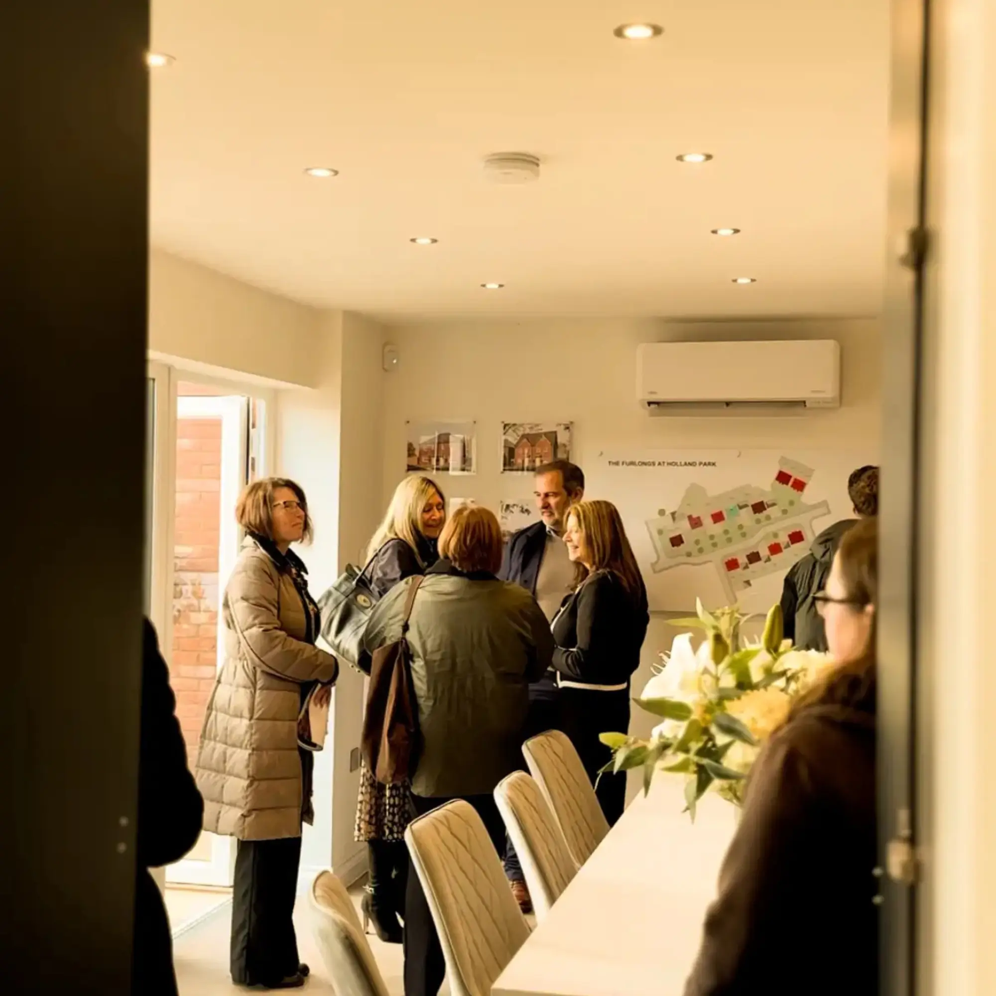 Visitors gathered inside the Sales Hub at The Furlongs, talking with Broadgate team members beside layout boards and development plans.