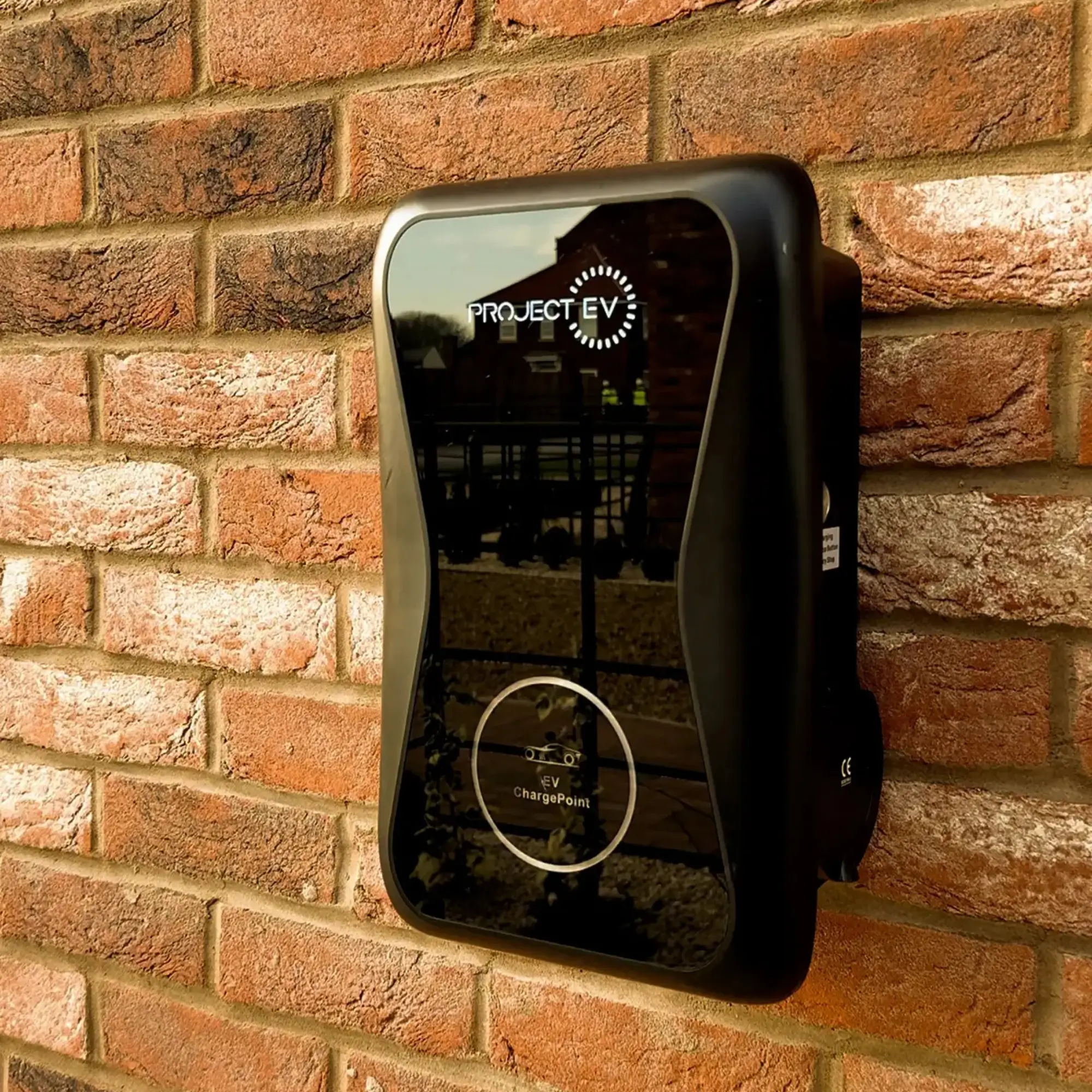 Exterior EV charging point mounted on a red-brick wall, part of the sustainable home features included at The Furlongs.