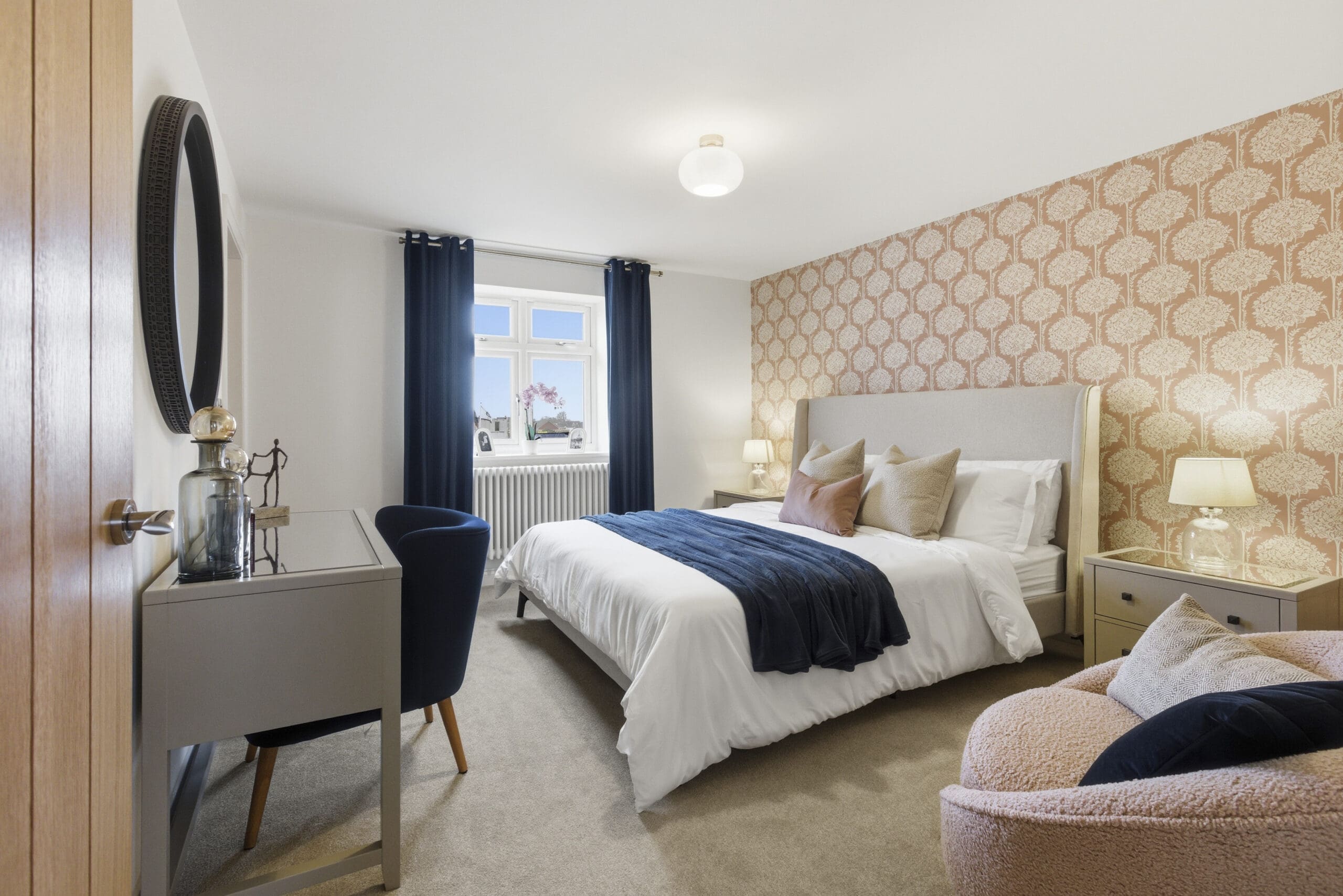 Bright master bedroom with feature wallpaper, upholstered bed, soft neutral décor, and large window providing natural light in a modern Broadgate Homes property.