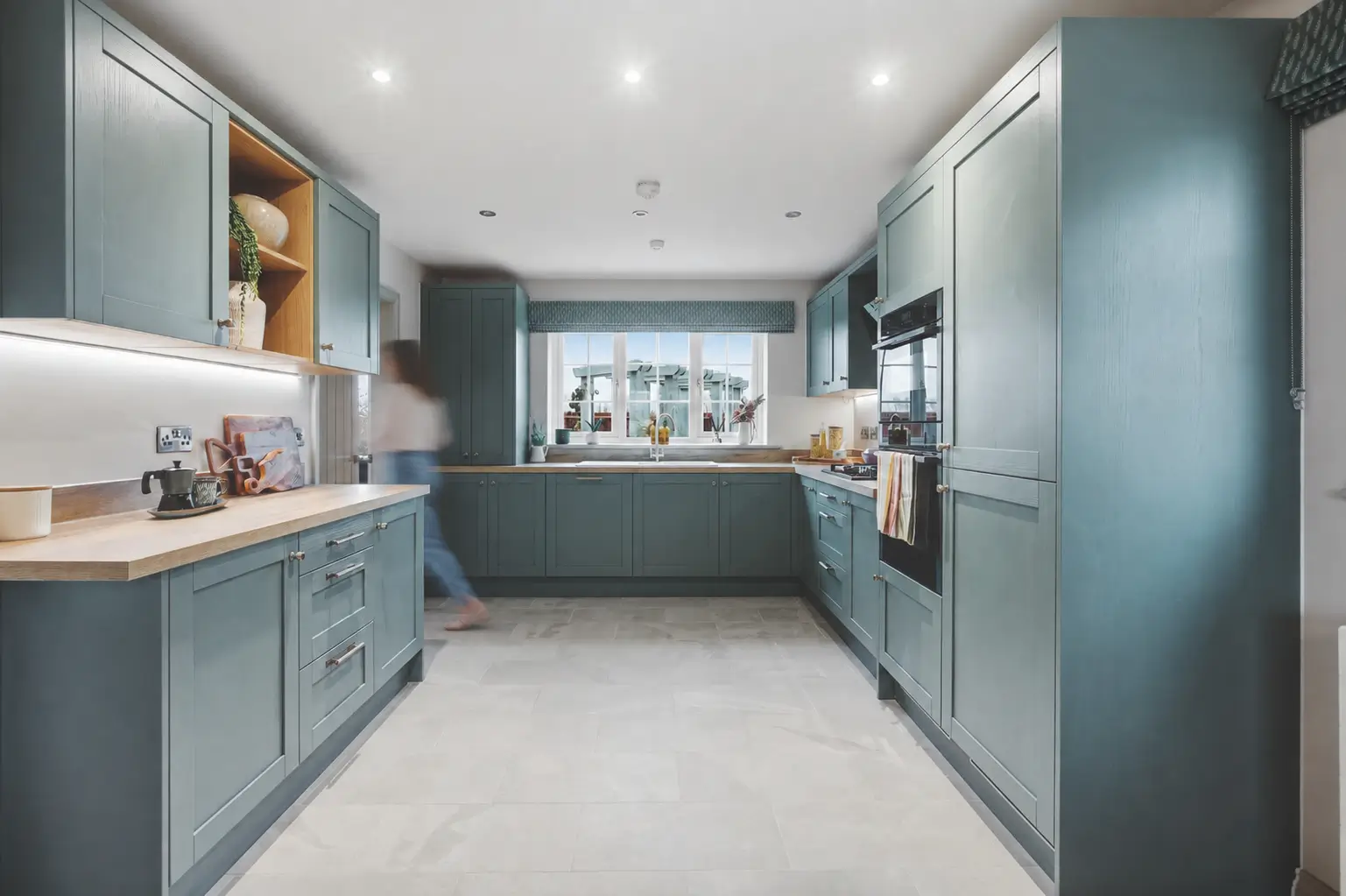 U-shaped kitchen at The Furlongs, Holland Park, Spalding, with teal shaker-style cabinetry, oak worktops, and integrated appliances.