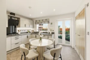 Kitchen diner at The Furlongs, Holland Park, Spalding, with pale grey cabinetry, dark stone worktops, and French doors opening onto the garden.