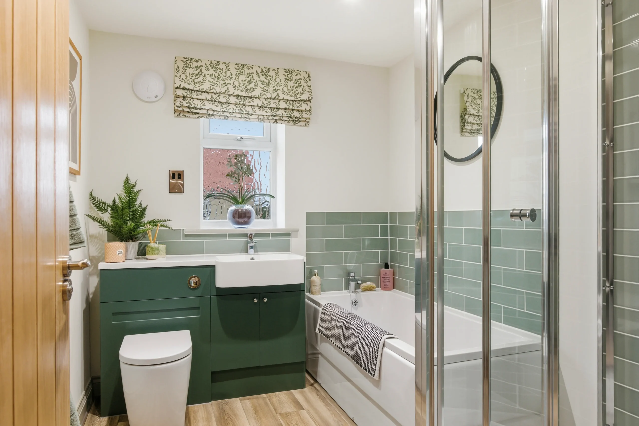 Family bathroom at Gleneagles Drive, Woodhall Spa, with sage green cabinetry, green metro tiles, and separate bath and shower.